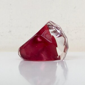 May include: A faceted, clear glass ring with a deep red, iridescent interior.