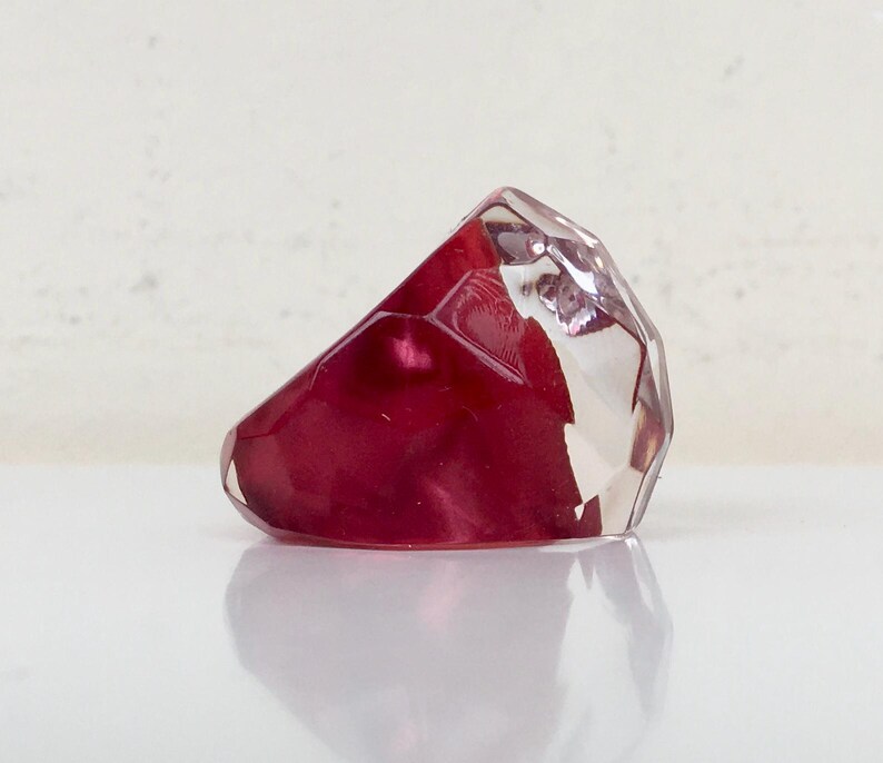 May include: A faceted, clear glass ring with a deep red, iridescent interior.