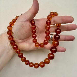 Puede incluir: Un collar largo de &aacute;mbar con cuentas redondas. El collar est&aacute; hecho de &aacute;mbar natural y tiene un color c&aacute;lido, similar al de la miel.