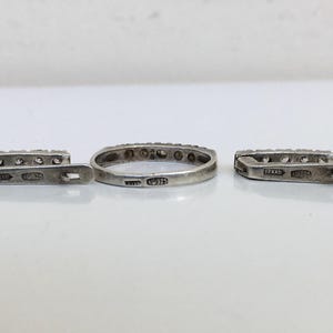 May include: A set of three silver rings with small clear stones set in the band. The rings are marked with the inscription "925" on the inside.