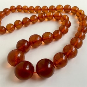 Puede incluir: Un collar largo de &aacute;mbar con cuentas grandes y redondas. Las cuentas son de un color marr&oacute;n c&aacute;lido y rico y tienen un acabado liso y pulido.