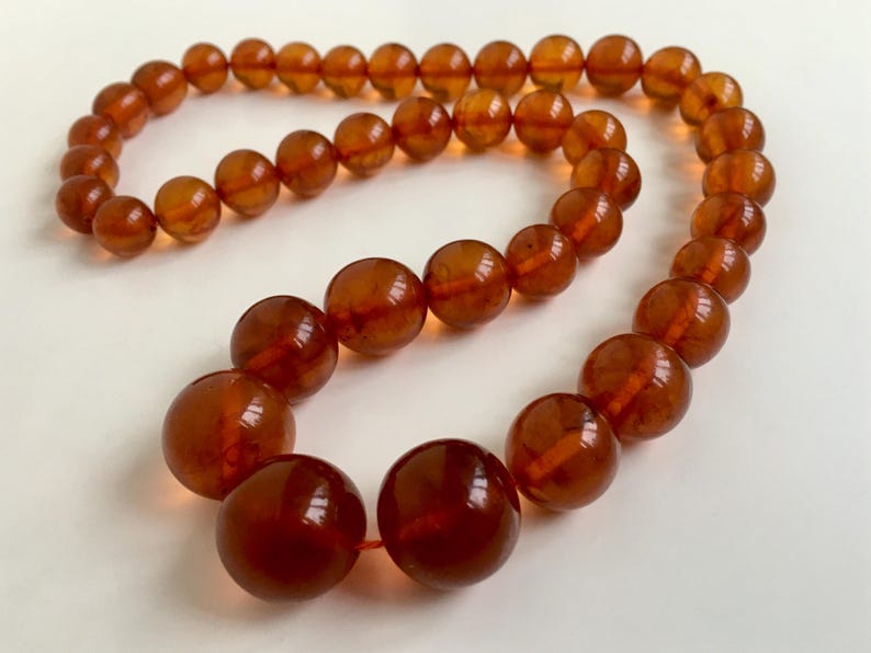 Puede incluir: Un collar largo de &aacute;mbar con cuentas grandes y redondas. Las cuentas son de un color marr&oacute;n c&aacute;lido y rico y tienen un acabado liso y pulido.