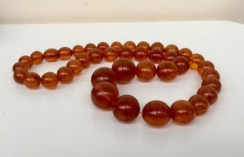 Puede incluir: Un collar largo de &aacute;mbar con cuentas grandes y redondas. Las cuentas son de un color marr&oacute;n c&aacute;lido y rico y tienen un acabado liso y pulido.