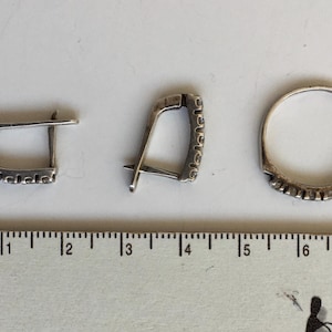 May include: Three silver rings with a decorative pattern. The rings are on a white surface with a ruler for scale.
