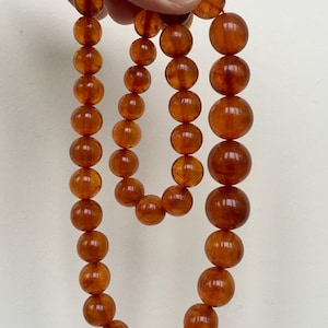 Puede incluir: Un collar largo de &aacute;mbar con cuentas redondas. El collar est&aacute; hecho de &aacute;mbar natural y tiene un color c&aacute;lido, similar al de la miel.