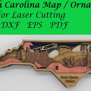 May include: A multi-layered wooden ornament in the shape of North Carolina. The ornament features laser-cut details of the state's landmarks and scenery, with the text "North Carolina Map / Ornament" and "Esse Quam Videri".