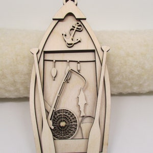 May include: A wooden cutout of a boat with fishing gear, including a fishing rod, net, and oars. An anchor is at the top of the boat.