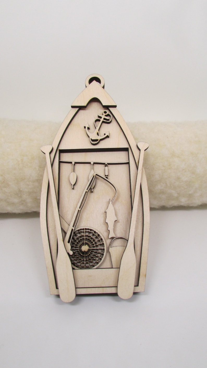 May include: A wooden cutout of a boat with fishing gear, including a fishing rod, net, and oars. An anchor is at the top of the boat.