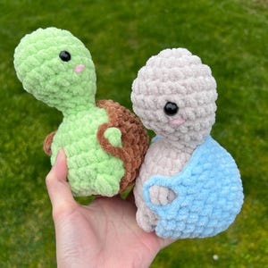 May include: Two crocheted stuffed toys, one green turtle and one light pink with a blue crocheted outfit.