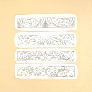 May include: Four rectangular embroidered patches with intricate gray line art designs. Each patch features a different Art Nouveau-inspired pattern, including floral and geometric motifs. The patches are on a cream-colored background.