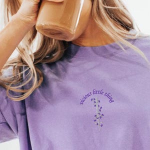 May include: A purple t-shirt with the text "vicious little thing" in a curved arc above a small floral graphic.