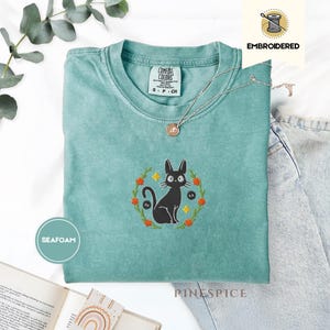 ジジの黒猫刺繍入りコンフォートカラーズ®Tシャツ - 気まぐれな魔女猫シャツ - 読書好きと猫好きのための、心地よく馴染みのある雰囲気