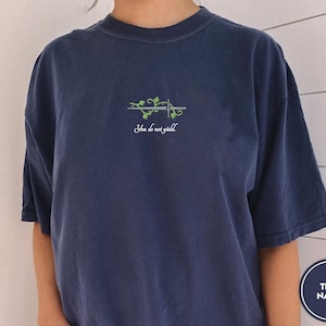 May include: A navy blue t-shirt with a green vine and sword graphic and the text "You do not yield".