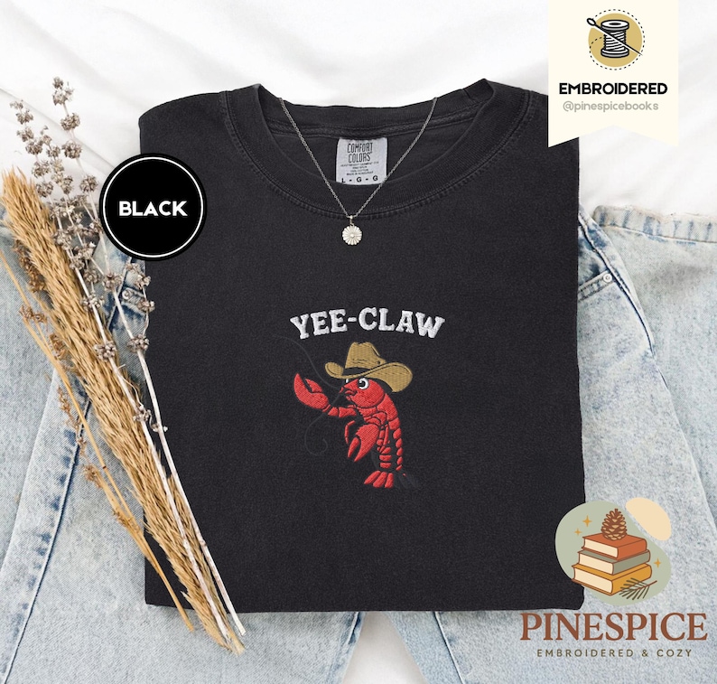 May include: Black sweatshirt with the embroidered phrase "YEE-CLAW" above a red lobster wearing a cowboy hat. The sweatshirt is a Comfort Colors brand. The word "BLACK" is in a black circle on the upper left.