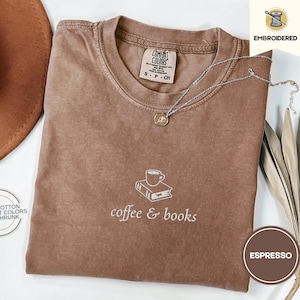 Op de afbeelding: Een bruin t-shirt met de tekst "coffee & books" geborduurd op de voorkant. Het shirt is gemaakt van 100% katoen en is voorgeshronken.