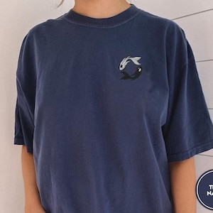 May include: A dark blue t-shirt with a yin yang symbol made of two fish, one black and one white. The text "TRUE NAVY" is in the lower right corner of the image.