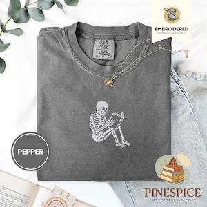 Skeleton reading book tee, embroidered skeleton coffee shirt, spooky book lover t-shirt, comfort colors 1717 fall vibes shirt, boo basket