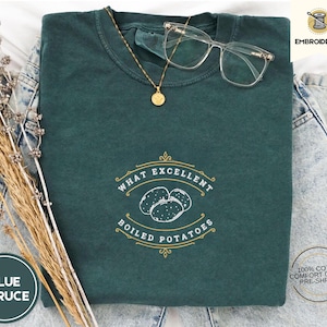 Może przedstawiać: Zielony T-shirt z haftem w kolorze złotym z napisem "What Excellent Boiled Potatoes" na przodzie. Koszulka wykonana jest w 100% z bawełny i jest wstępnie skurczona.