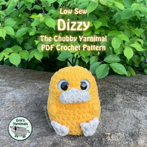 May include: A crocheted yellow duck with black eyes and a white beak. The duck is sitting on a rock with green leaves in the background. The text "Low Sew Dizzy The Chubby Yarnimal PDF Crochet Pattern" is above the duck. The text "@erinsyarnimals" is below the duck.