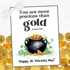 Op de afbeelding: Een witte kaart met de tekst "You are more precious than gold" en "Isaiah 13:12". Een zwarte pot gevuld met gouden munten is geïllustreerd met groene klavers. De tekst "Happy St. Patrick's Day!" staat onderaan de kaart.