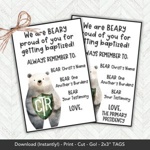 May include: Two rectangular tags with text and a watercolor bear illustration. The tags read "We are BEARY proud of you for getting baptized!" and include reminders. A twine bow is at the top. The tags are 2x3 inches.