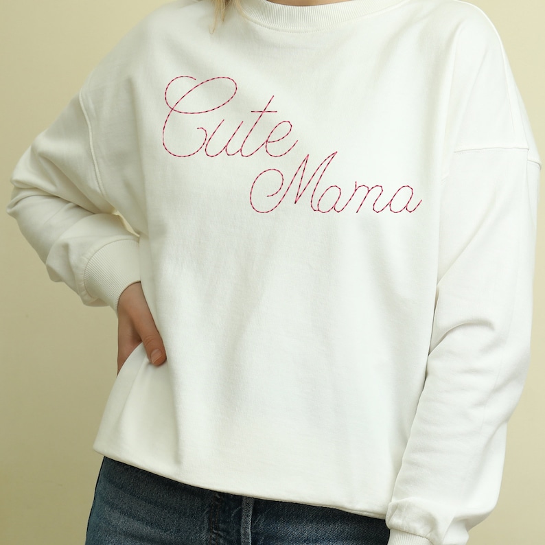 May include: White sweatshirt with a pink embroidered design that says "Cute Mama".