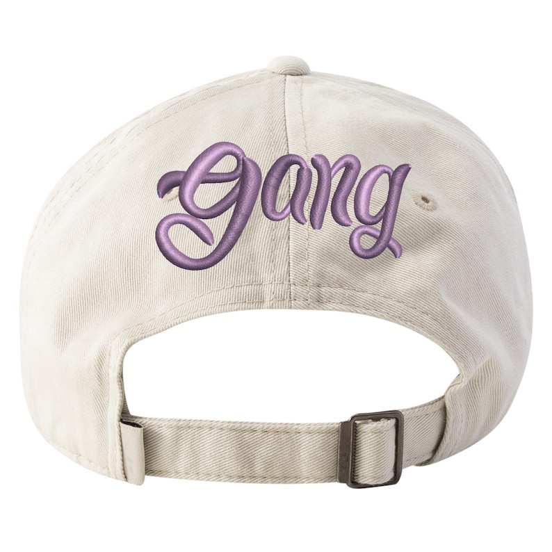 May include: A beige baseball cap with an embroidered purple "Gang" logo on the back.