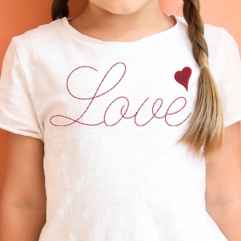 May include: White t-shirt with red embroidered lettering that says "Love" and a small red heart.