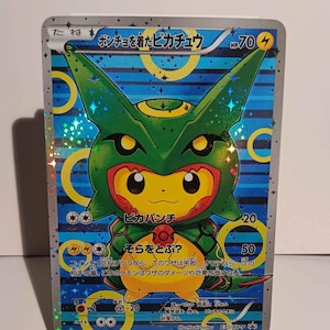 May include: A Pokemon trading card featuring Pikachu wearing a green and red poncho with the text "ポンチョを着たヒカチュウ" and "HP70". The card has a blue and white background with stars and circles.
