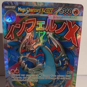 May include: A holographic Mega Charizard X EX trading card. The card features a blue and red dragon-like creature with Japanese text. The card has a HP of 360 and the attack is Inferno X.