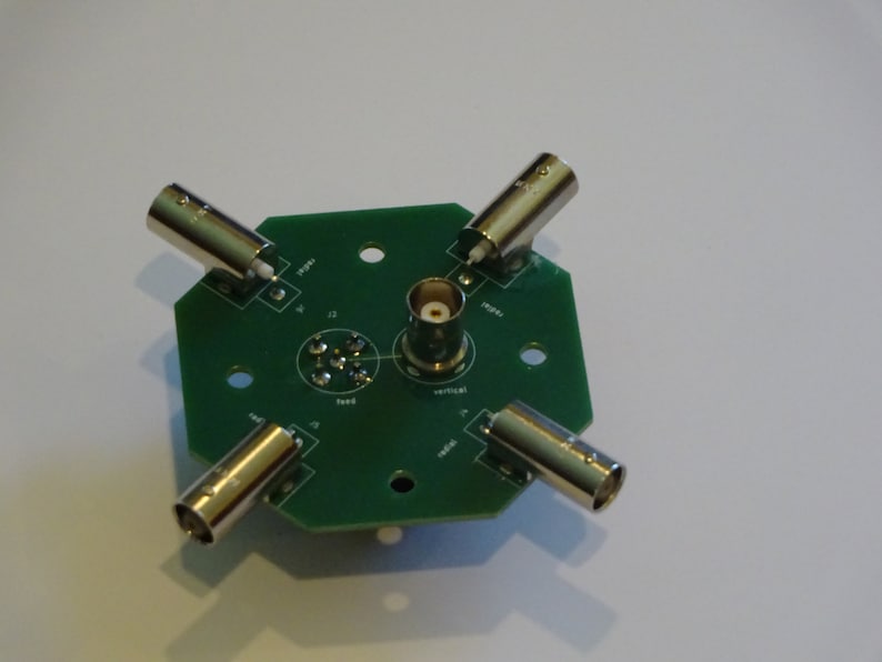 May include: A green circuit board with five BNC connectors and a central female BNC connector. The board is labeled with the words "feed", "vertical", "rotate", "type", and "12".