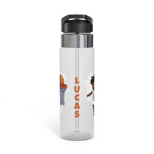 May include: A clear plastic water bottle with a black lid and a silver band around the middle. The bottle has a straw and a basketball themed design with the name "LUCAS" printed on the side.