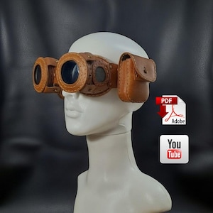 May include: Steampunk-style goggles with brown leather and metal accents. The goggles feature two large lenses, a central mesh section, and small side pouches. The design includes rivets and a leather strap, creating a vintage aesthetic.