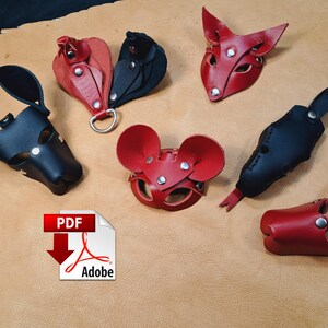 May include: A collection of handcrafted leather animal-themed masks and accessories in red and black. The set includes various ear shapes, snout designs, and metal hardware fasteners, arranged on a tan leather hide background.