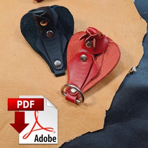 May include: A collection of leather key organisers and holders in black and red. These items feature silver-toned metal snaps and a circular metal ring for attachment. The leather pieces are shaped like teardrops and include a PDF Adobe icon.