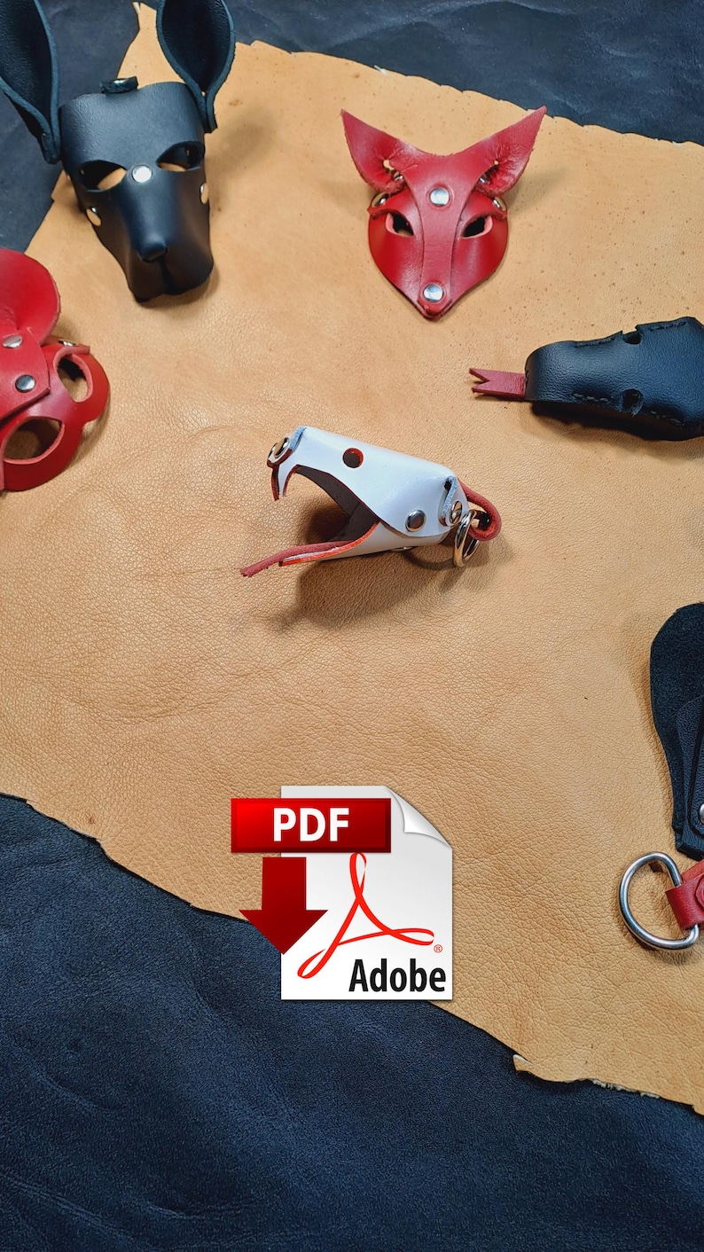May include: A collection of leather animal-shaped keychains including a black dog mask, a red fox mask, a white snake head with a red tongue, and other leather pieces arranged on a tan leather hide. A PDF Adobe icon is overlaid at the bottom.