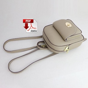 May include: A beige leather backpack with a flap closure and a gold-toned buckle. The backpack has a small pocket on the front and adjustable straps.