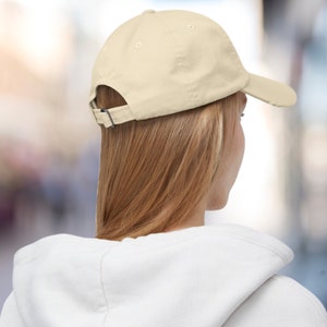 K&ouml;nnte beinhalten: Eine einfarbige, hellbeige Baseballkappe mit einem gebogenen Schirm. Die Kappe ist aus weichem Baumwollstoff gefertigt und hat einen verstellbaren Riemen hinten.