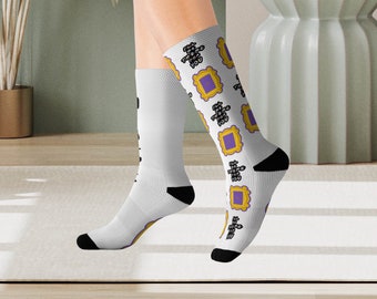 May include: White socks with a purple and yellow pattern of the iconic "Friends" show logo. The logo is a purple door inside a yellow frame.