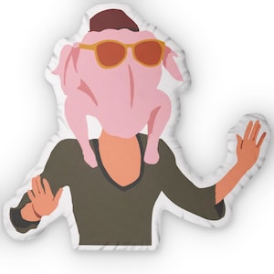 May include: A decorative cushion featuring a cartoon illustration of a person wearing a turkey costume. The person is wearing sunglasses and a hat. The cushion is white with a stitched edge.