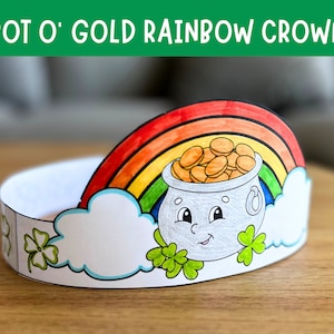 Puede incluir: Una corona de papel con forma de arcoíris con un pote de oro al final. El pote de oro tiene una cara sonriente y está lleno de monedas de oro. La corona está decorada con tréboles.