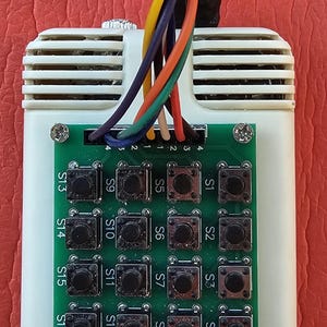 May include: A white rectangular electronic control unit featuring a green circuit board with sixteen black push buttons labeled S1 through S16. A bundle of multicolored wires, including orange, yellow, blue, and green, extends from the top.