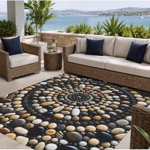 May include: A rectangular area rug featuring a repeating circular pattern of smooth, multi-colored river stones in shades of white, tan, brown, gray, and black against a dark background, creating a textured visual effect on the floor surface.