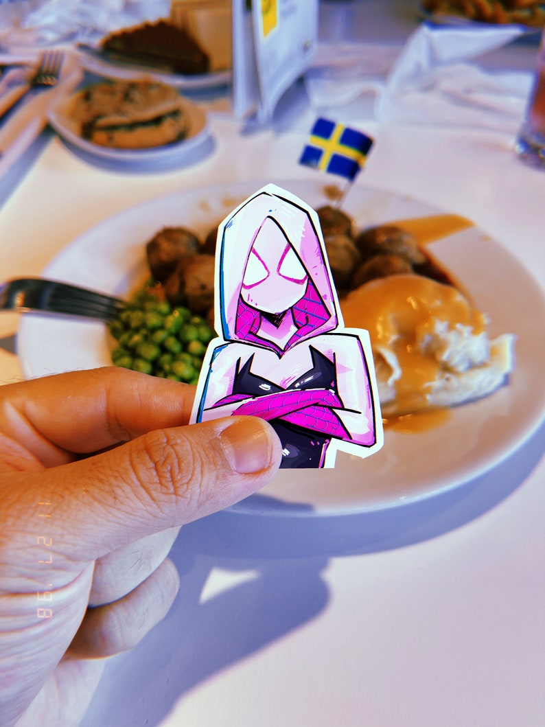 May include: A pink and black cartoon character with a white hooded jacket and a black mask. The character is holding their arms crossed in front of them. The character is on a white sticker.