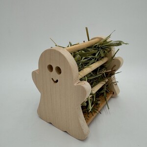 Op de afbeelding: Een houten hooi-voederbak in de vorm van een spook met een glimlachend gezicht, gevuld met gedroogd gras.