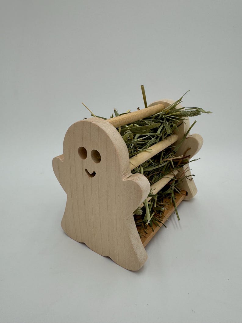 Op de afbeelding: Een houten hooi-voederbak in de vorm van een spook met een glimlachend gezicht, gevuld met gedroogd gras.