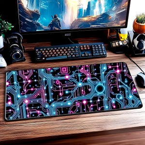 May include: A black rectangular mouse mat featuring a circuit board design in neon blue, pink, and purple. The mat is on a wooden desk with a keyboard, monitor, and other computer accessories.