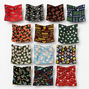 May include: A collection of twelve square fabric bowl cozies featuring various sports-themed patterns, including team logos for the Washington Capitals, Ravens, Orioles, Seahawks, and Commanders, alongside prints of footballs, golf balls, baseballs, and soccer balls.
