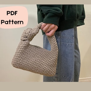 Op de afbeelding: Een PDF-patroon voor een gehaakte handtas met een geknoopte handvat. De tas is lichtbruin van kleur en heeft een textuurweefsel.