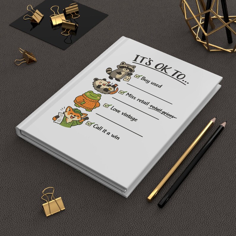 Pu&ograve; includere: Un diario bianco con il testo "IT'S OK TO..." e illustrazioni di animali. Il diario include caselle di controllo per "Buy used", "Miss retail", "Love vintage" e "Call it a win". Sono presenti anche matite e fermagli dorati e neri.